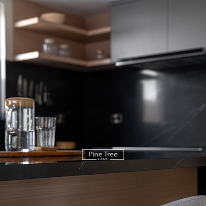 Water pitcher and glasses on a wooden tray on black marble island