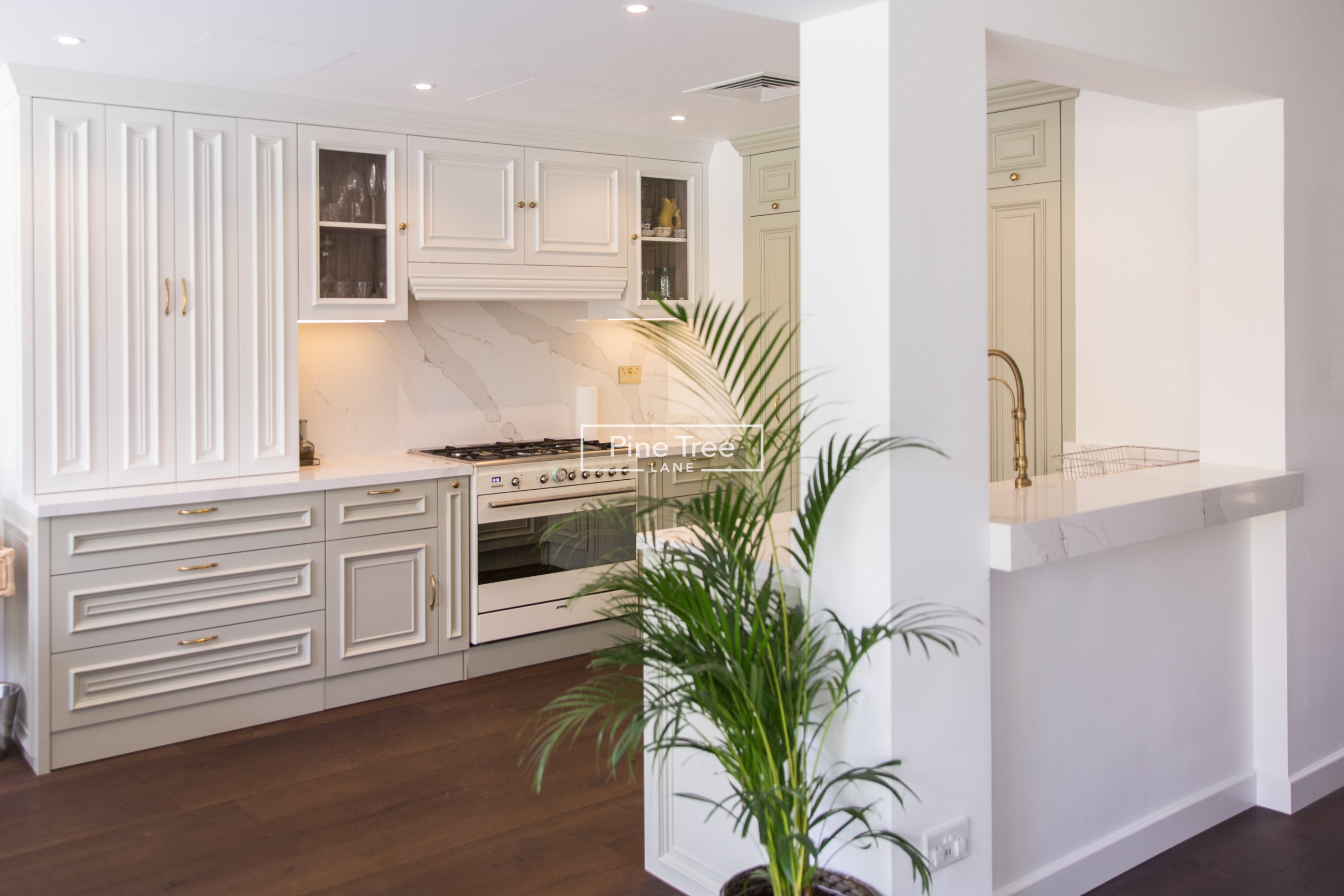 kitchen with sage and white cabinets and brass fixtures