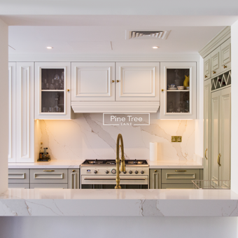 kitchen with sage and white cabinets and brass fixtures