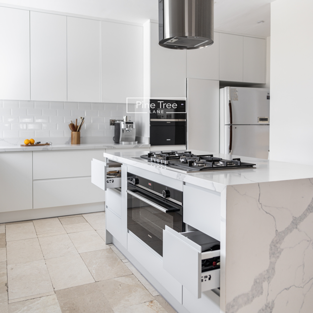 Kitchen with white cabinetry and marble countertops.