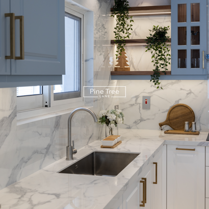 kitchen with pastel blue drawers, brass handles, and marble countertop