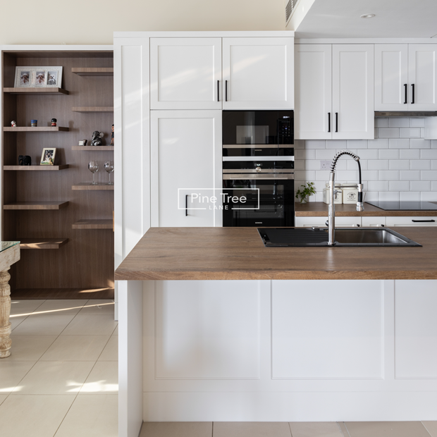 Contemporary kitchen with crisp white cabinetry and wood countertop