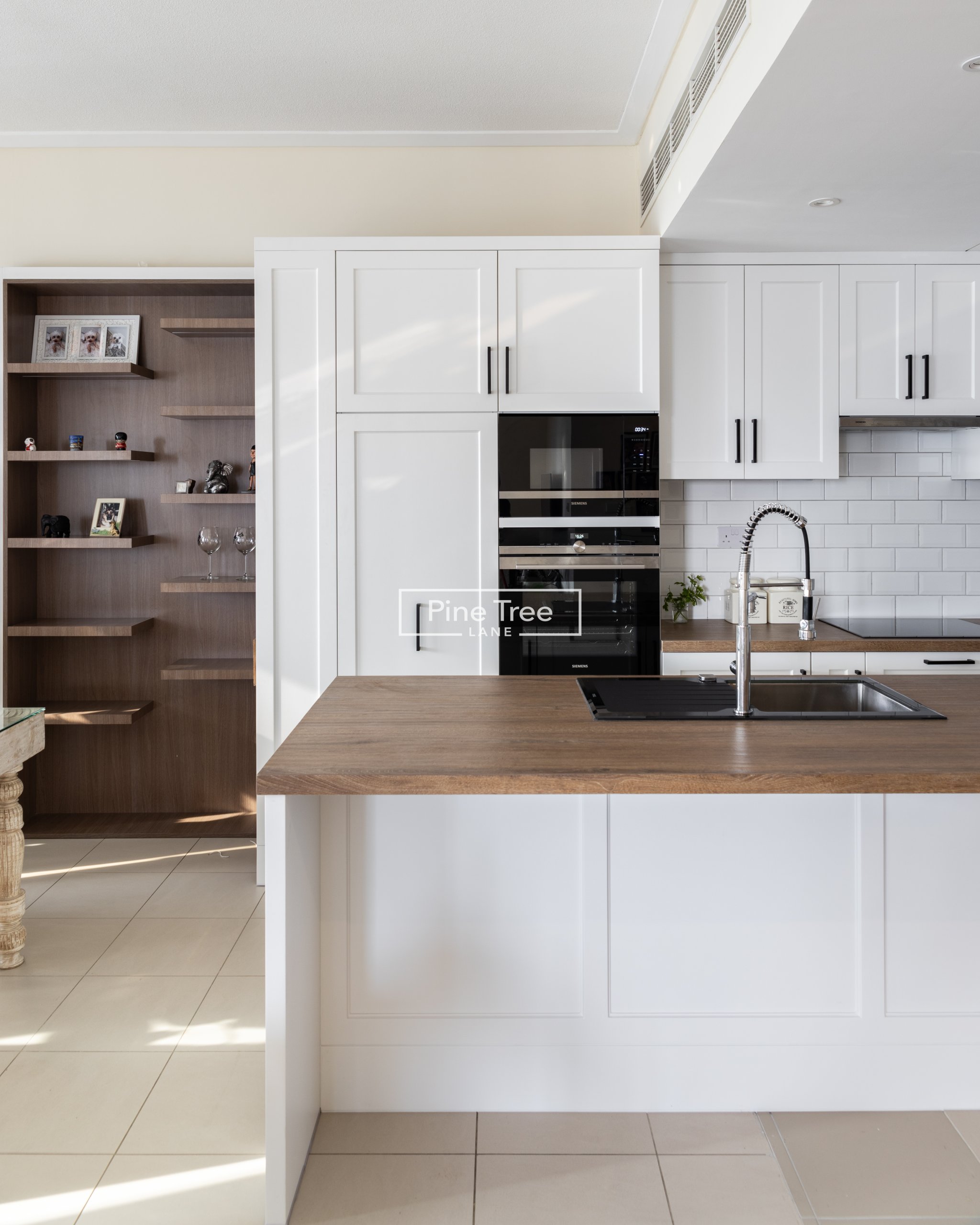 Kitchen featuring sleek white cabinets and open wood shelves
