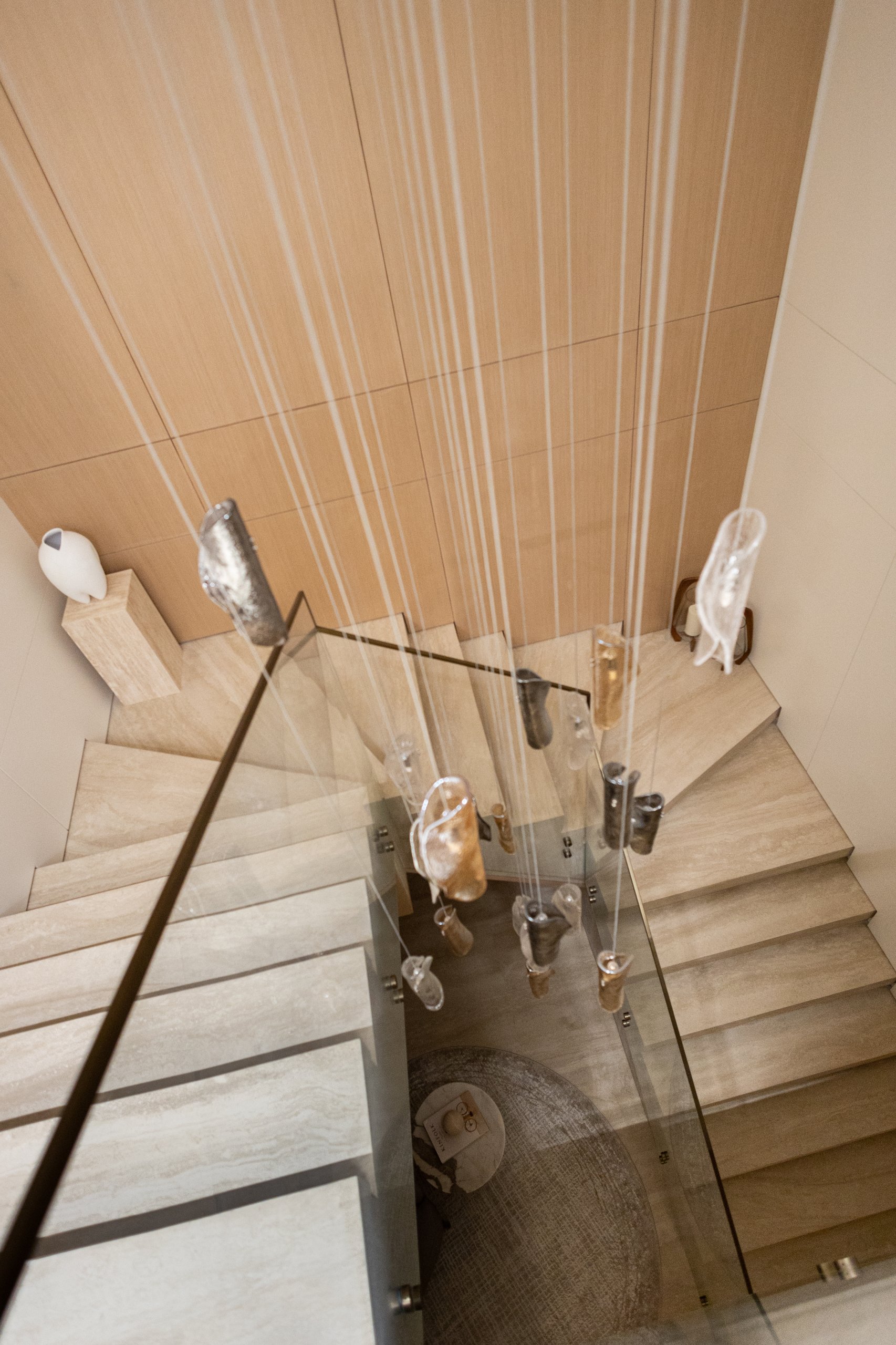 Modern stone stairs with glass and black handrail.