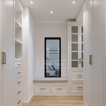 White walk-in wardrobe with gold hardware and bench