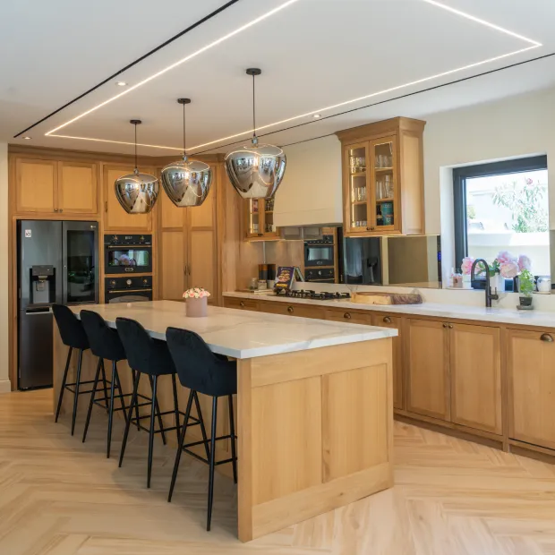 Spacious open kitchen with island, leather bar stools, and wooden cabinetry