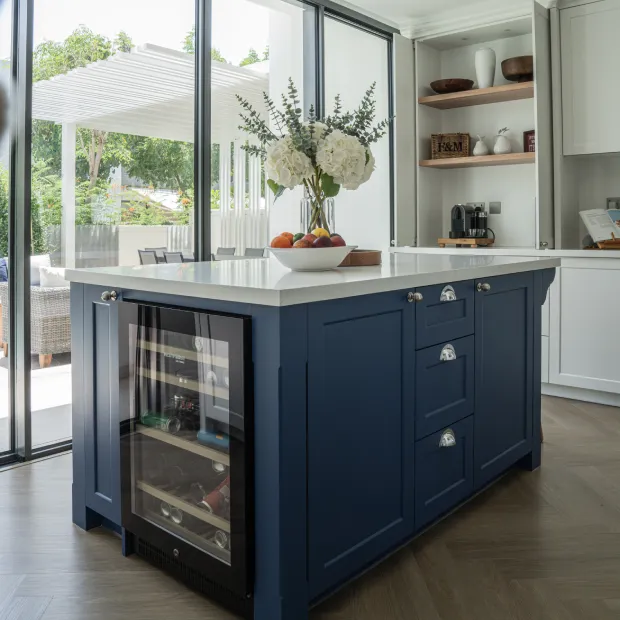 Blue kitchen island featuring integrated glass wine cooler and marble top