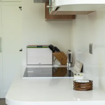 White kitchen countertop with knife block, wall outlets, and integrated cooktop