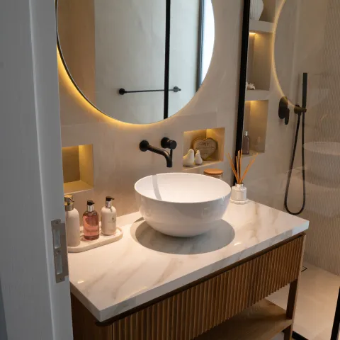 Modern bathroom vanity with vessel sink, marble countertop, and backlit circular mirror