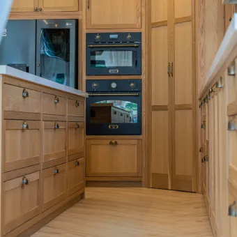 Custom tall wooden pantry cabinets with integrated built-in ovens