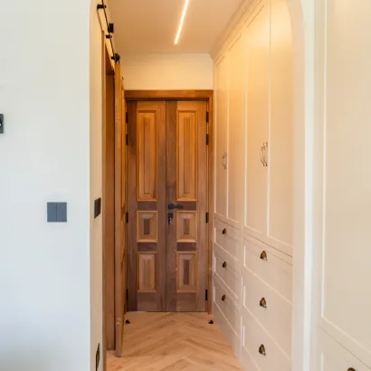 Solid wooden interior door installed in a modern hallway with light wood flooring