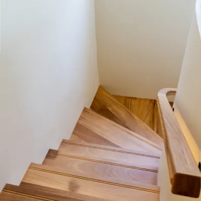 Modern wooden staircase with glass balustrade and built-in wall niche