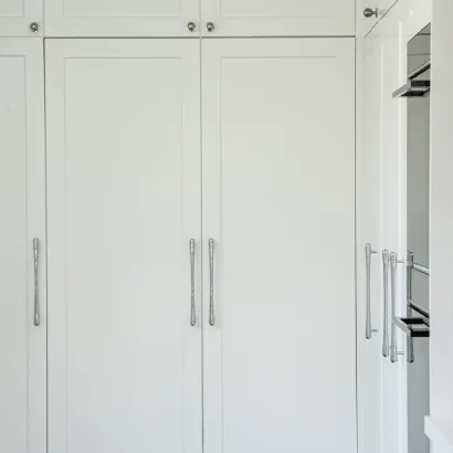 Custom floor-to-ceiling white fitted wardrobes with long silver handles