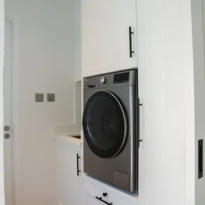 Modern laundry room with front-load washing machine and white custom cabinets