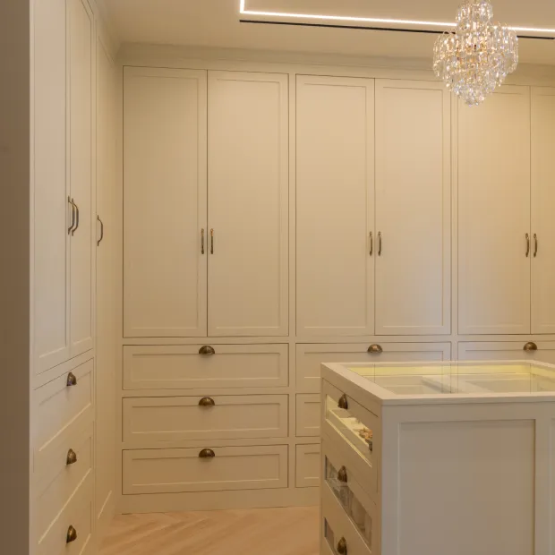 Custom white fitted wardrobes with glass chandelier in walk-in closet