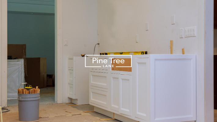 Kitchen renovation project featuring newly installed white cabinets ready for finishing